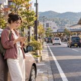 Foreign resident considering a car trip beside a regional train station in Japan