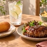 Corn dog, lemon-lime soda, hamburger steak, and fries on a table