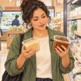 Illustration of a shopper comparing pale and reddish miso tubs in a Japanese supermarket